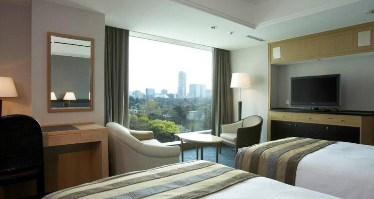 Hotel room interior with a view of the city skyline through a window.