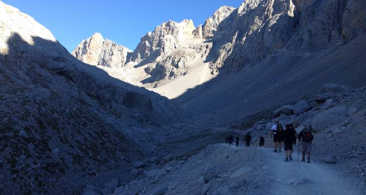 Randonneurs marchant le long d'un sentier dans un paysage montagneux rocheux.