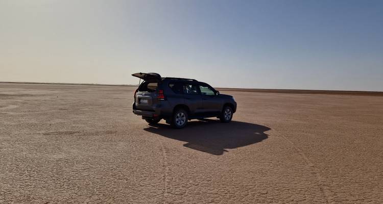 SUV unique garé dans un vaste désert ouvert et plat.
