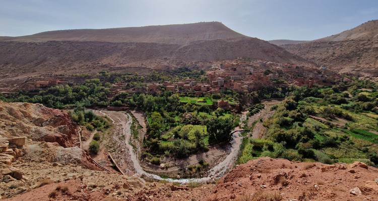 Vue panoramique sur une vallée avec une rivière sinueuse et une végétation verdoyante.