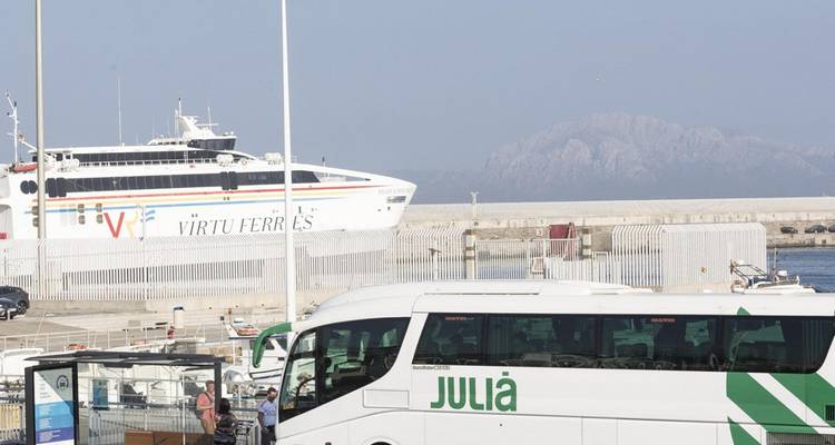 Bus and ferry at a harbor with a distant mountain.