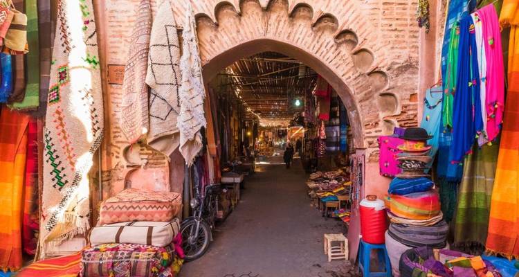 Colorful market street with vibrant textiles and a person in the distance.