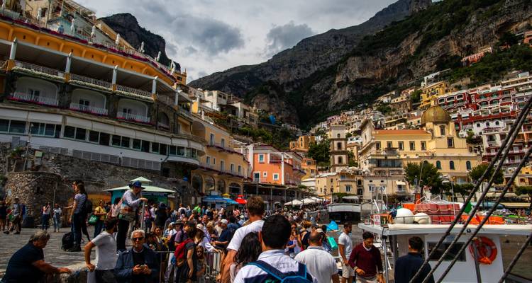 Place portuaire animée de Positano avec des maisons colorées à flanc de falaise qui dominent les foules et les bateaux.