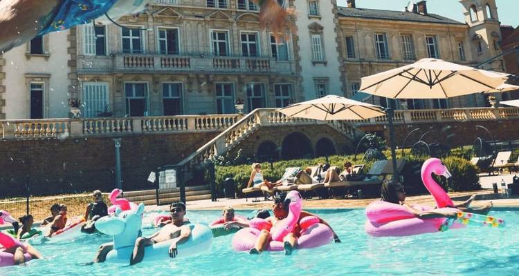 Fiesta junto a la piscina llena de vida con huéspedes relajándose en flamencos inflables en un gran castillo