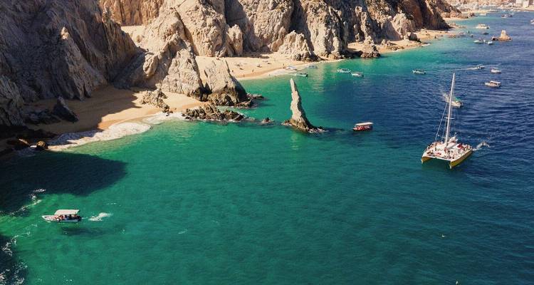 Een prachtige baai met boten en helder water tegen rotsachtige kliffen.