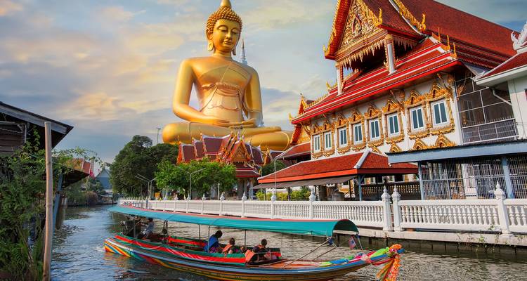 Statue dorée de Bouddha et temple avec un bateau sur le canal en Thaïlande.