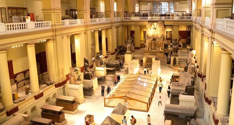 Intérieur d'un musée avec des artefacts égyptiens et des visiteurs admirant les expositions.