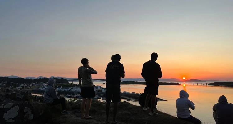 Silhouette de personnes regardant un coucher de soleil au-dessus d'un plan d'eau.