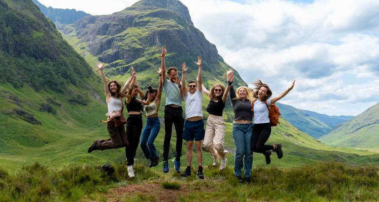 Groupe sautant de joie dans un paysage montagneux.