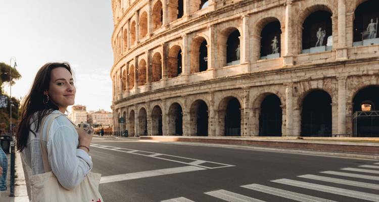 Una persona con una cámara parada frente al Coliseo.