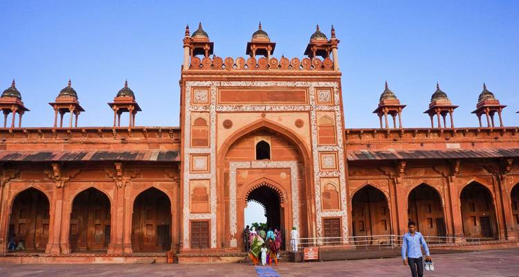 The imposing entrance of a grand fort with people walking in Agra.