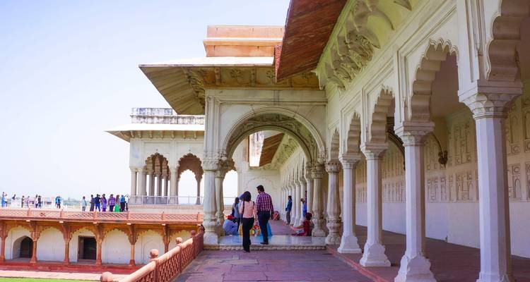 A white marble pavilion with people exploring in Agra Fort.