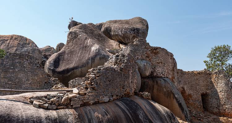 Ancient rock formations and ruins against a clear blue sky.