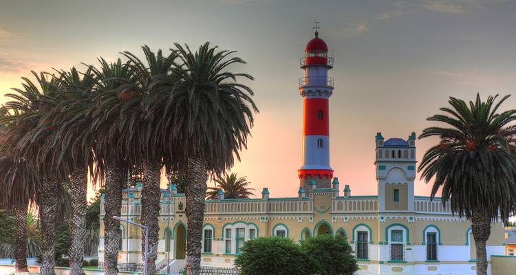 Un phare et des palmiers au coucher du soleil.