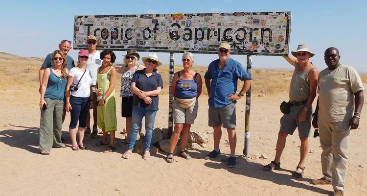 Toergroep die poseert bij het bord van de Steenbokskeerkring in de Namib-woestijn