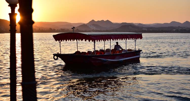 Boot op een meer met zonsondergang op de achtergrond.
