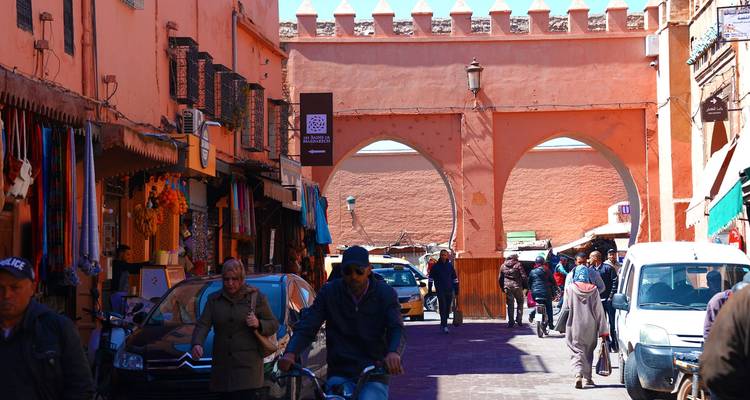 Street scene in a Moroccan city with an archway, people walking, and a cyclist