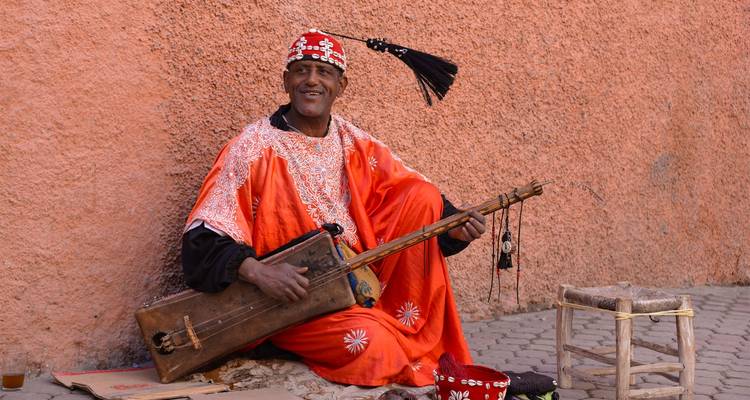 Individual in traditional Moroccan attire sitting with an instrument