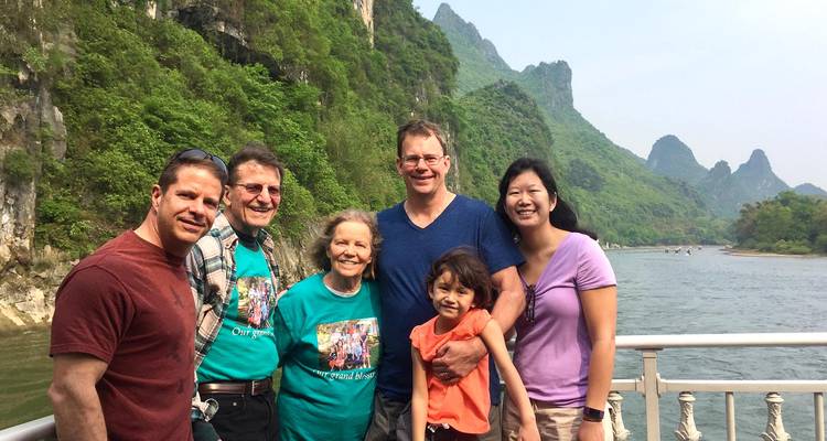Group posing on a boat with a river and karst mountains.