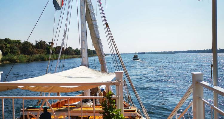 Segelboot auf einem breiten Fluss mit einem sichtbaren Boot in der Ferne.
