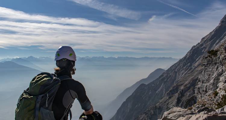 Klimmer met helm geniet van het uitzicht vanaf een bergrand.