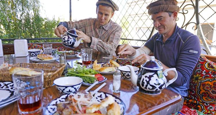 Two men enjoying a traditional meal with local pottery and food.