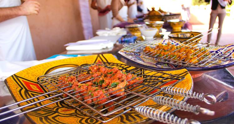 Een levendig Noord-Afrikaans gegrild vleesgerecht geserveerd op kleurrijke borden.