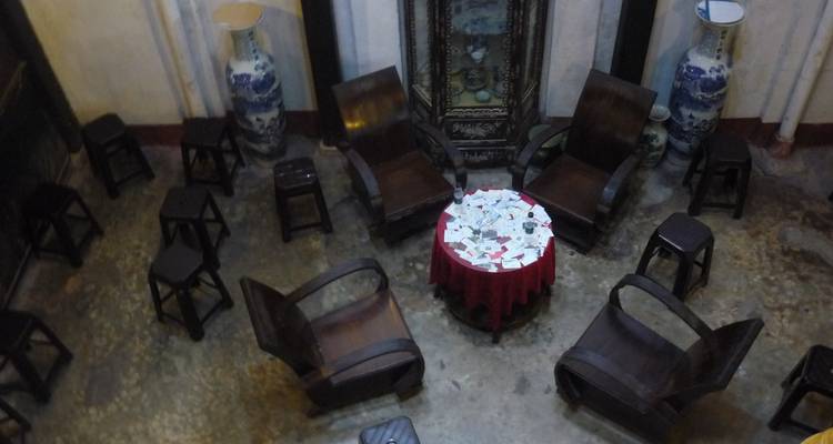 Binnenruimte met een tafel omringd door houten stoelen en traditionele decoratie.