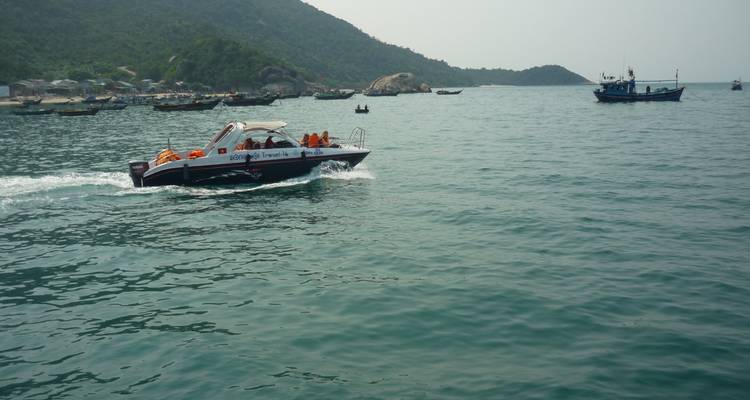Speedboat op het water met toeristen die zwemvesten dragen in de buurt van een kustgebied.