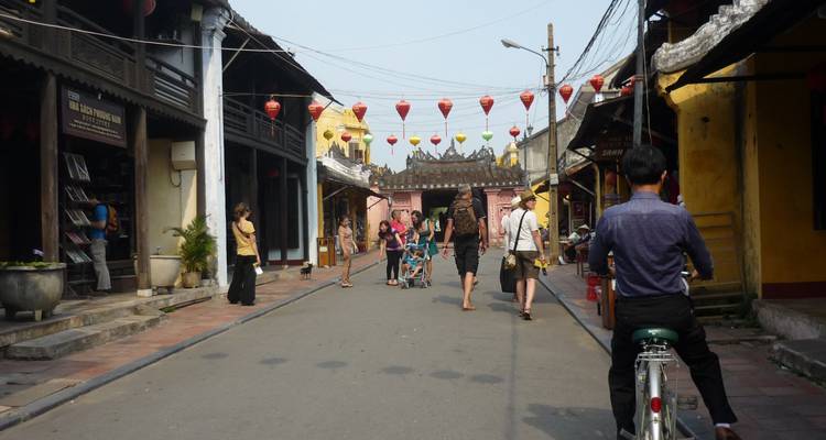 Straat met mensen die door een historisch gebied naar een versierde poort toe lopen.