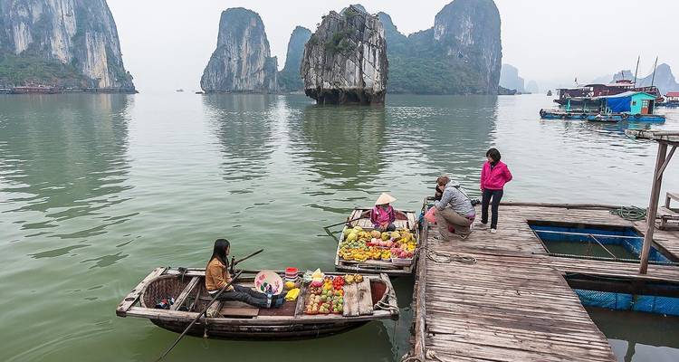 Menschen, die Früchte auf Booten in der Halong-Bucht kaufen und verkaufen.
