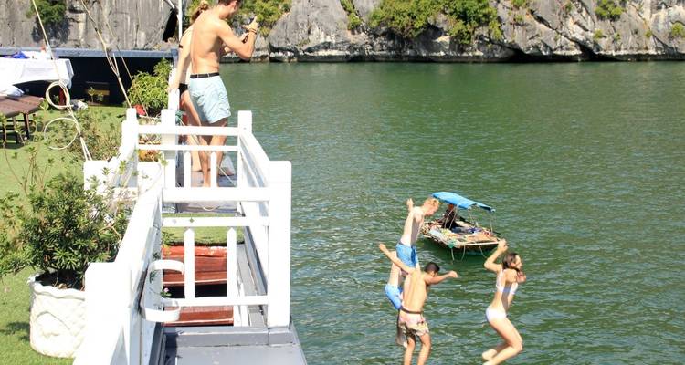 Menschen, die von einem Boot ins Wasser springen, mit malerischer Aussicht.