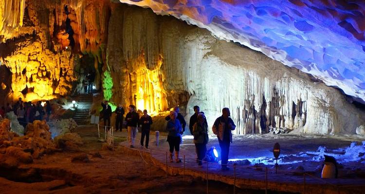 Touristen erkunden eine bunt beleuchtete Höhle.