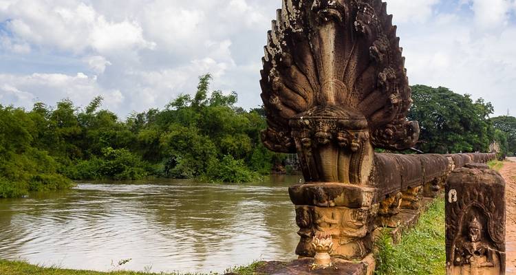 Ancient serpent statue on a bridge over a river.