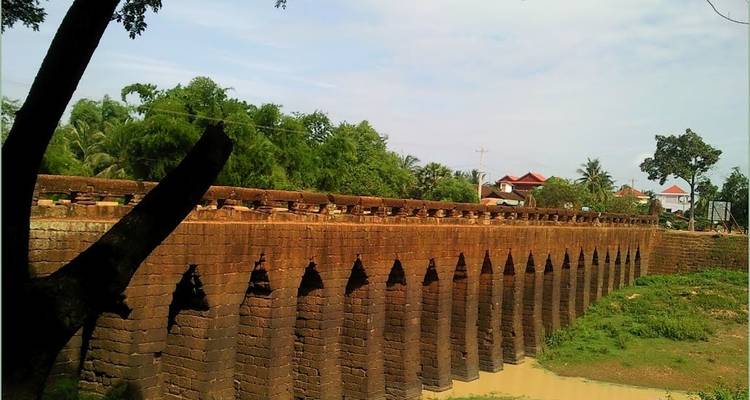 Old brick bridge with many arches over a dry riverbed.