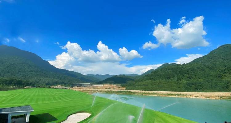 Schilderachtige golfbaan met sproeiers en een meer.