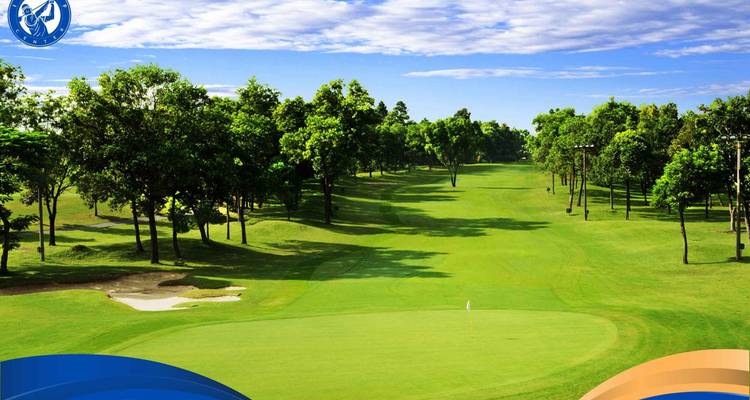 Langer Golfplatz gesäumt von Bäumen und unter klarem Himmel.