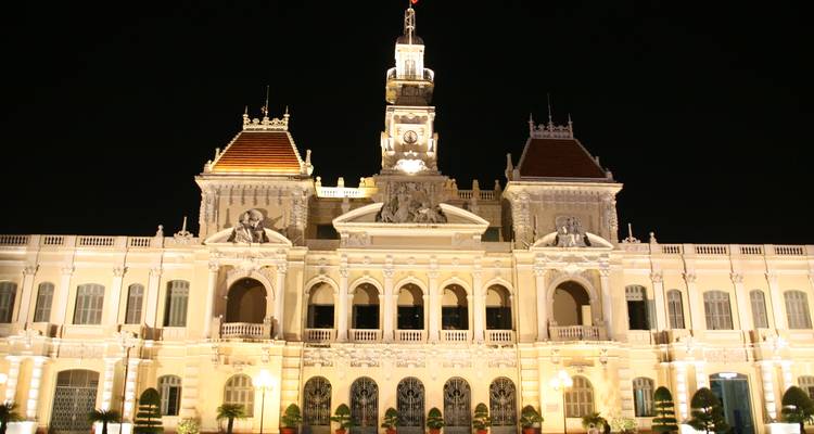 El Ayuntamiento de Ho Chi Minh iluminado brilla elegantemente contra el oscuro cielo nocturno.