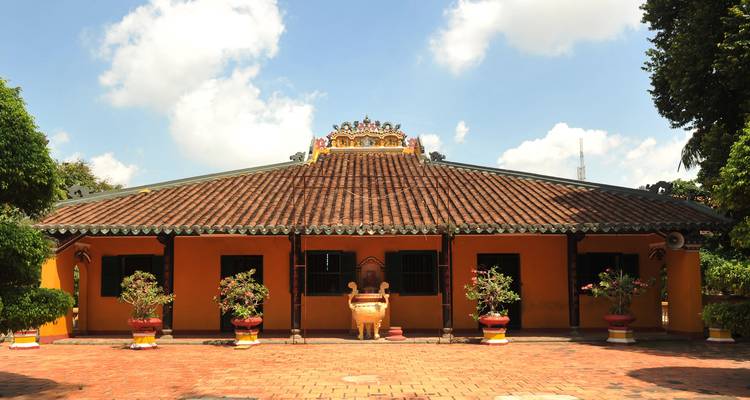 Edificio de templo con paredes amarillas tradicionales y detalles decorativos en el techo bajo un cielo despejado.