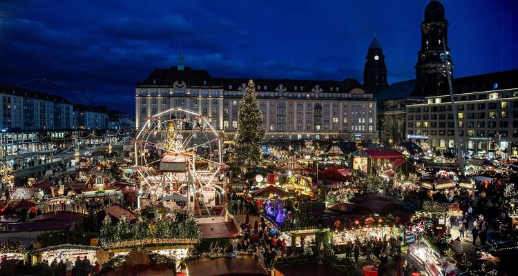 Marché de Noël animé avec une grande roue et des foules festives.