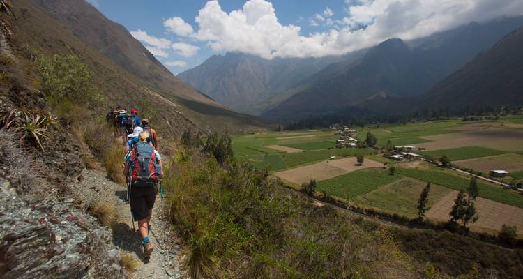 Group of hikers walking along a mountain trail with scenic views.