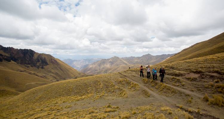 Hikers walking on a mountain path with a vast valley view.