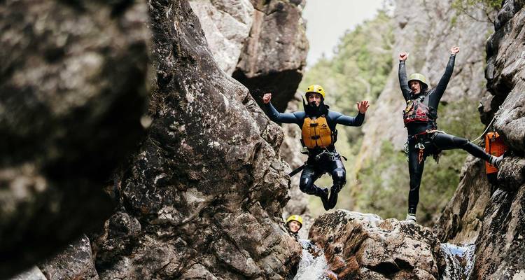 Zwei Personen in Schutzausrüstung springen auf Felsen.