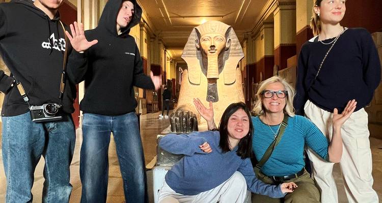 Group posing near statues inside a museum.
