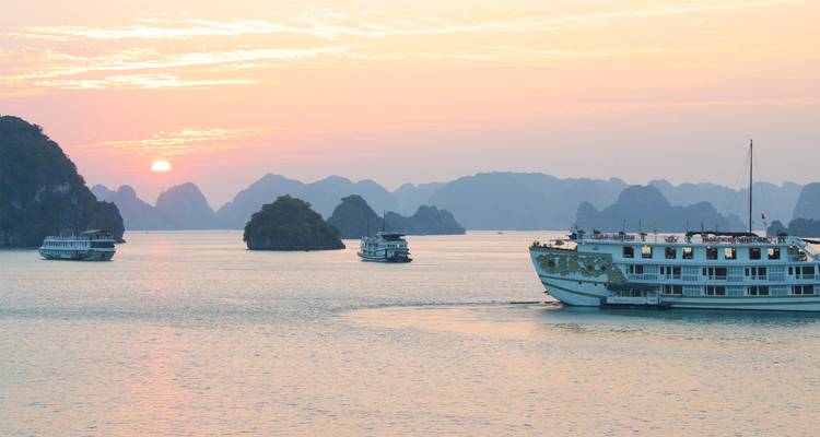 Schilderachtig uitzicht op boten in Halong Bay tijdens zonsondergang.