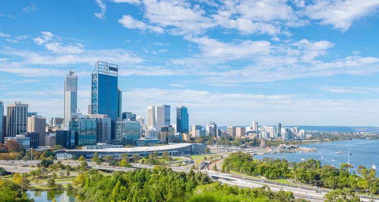 Skyline von Perth mit blauem Himmel und grünem Vordergrund.
