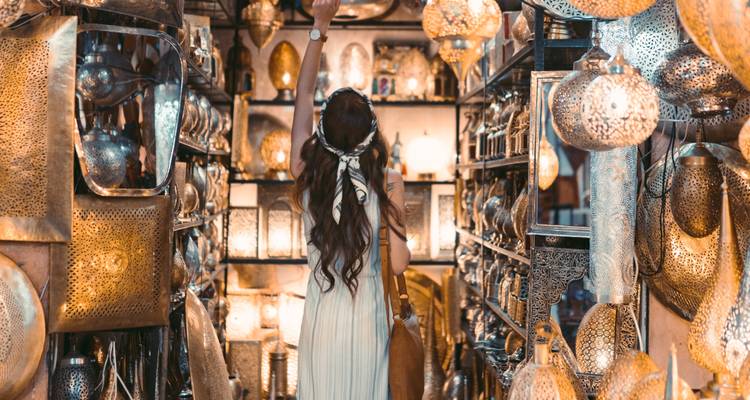 Persoon die door een markt bladert vol met metalen lampen en handwerk.