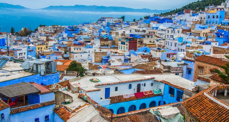 Vista de un pueblo con edificios pintados de azul extendidos por una ladera.