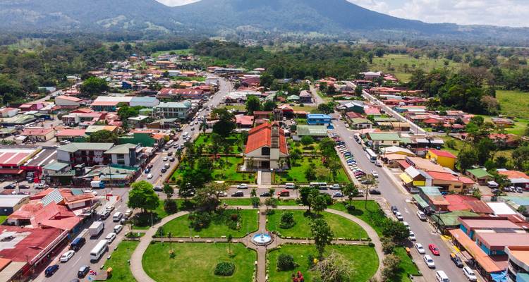Luftaufnahme einer Stadt mit Bäumen und Bergen.