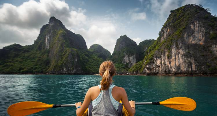 Mujer haciendo kayak en una bahía pintoresca con acantilados de piedra caliza.